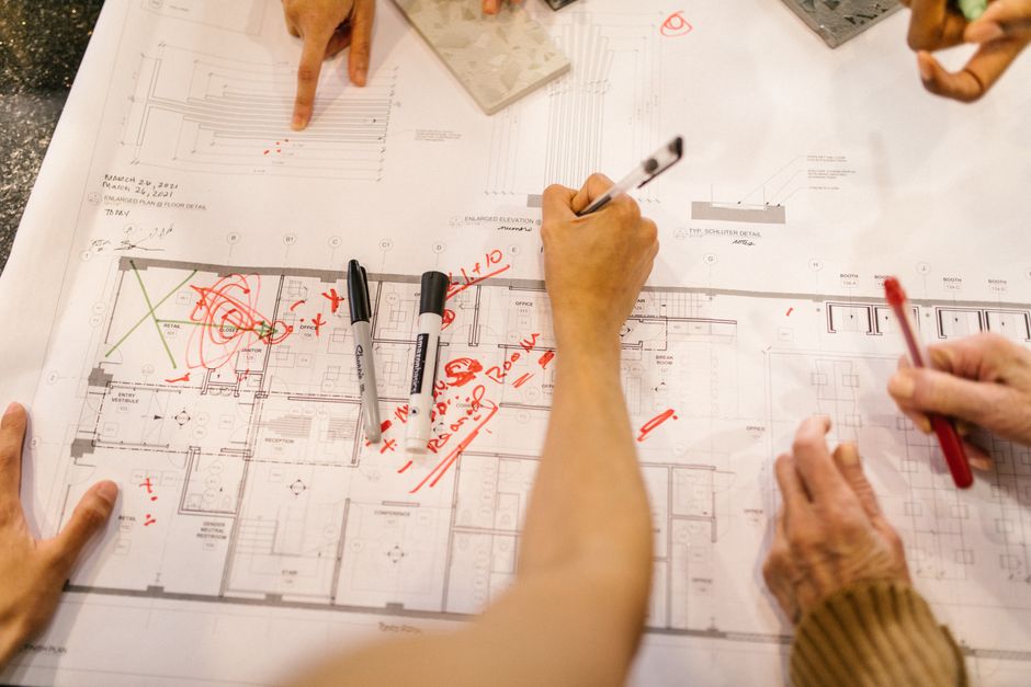 Team working together on architectural blueprints, marking plans with red ink.